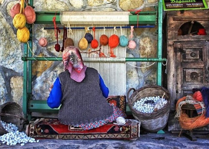 Local woman weaving carpets with colorful yarn in Bodrum village