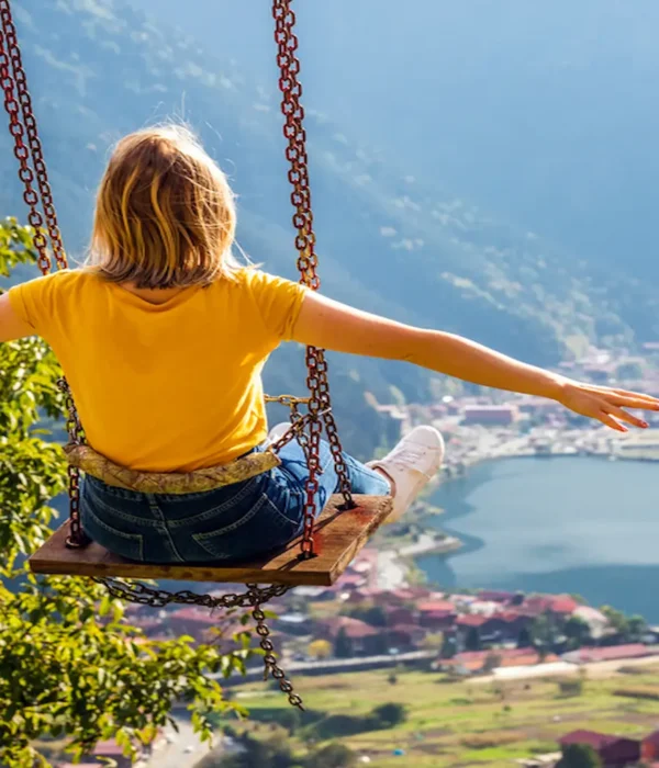 Traveler on a swing overlooking Uzungol lake and village