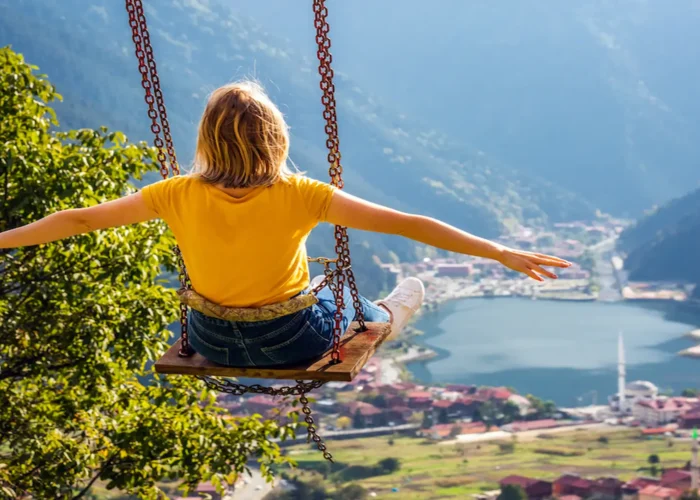 Traveler on a swing overlooking Uzungol lake and village