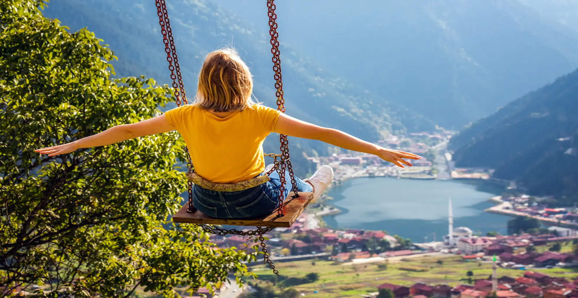 Traveler on a swing overlooking Uzungol lake and village