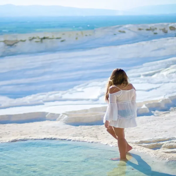 Tourist walking barefoot on Pamukkale travertine terraces
