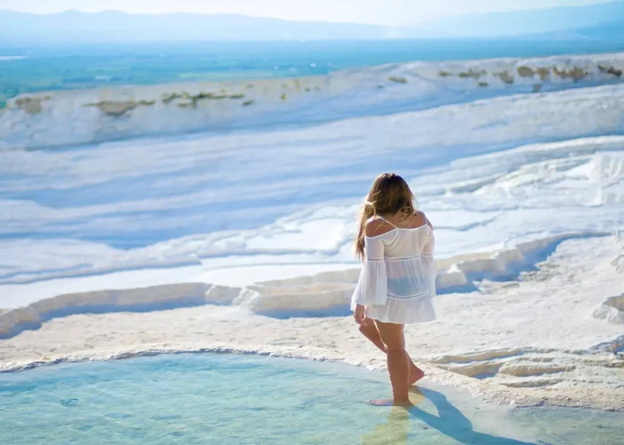 Tourist walking barefoot on Pamukkale travertine terraces