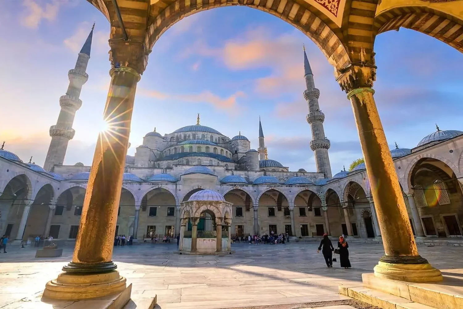 Courtyard of the Blue Mosque with arches and minarets during sunset