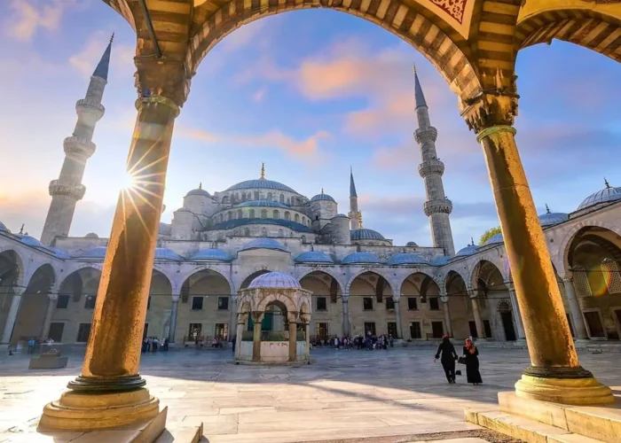 Courtyard of the Blue Mosque with arches and minarets during sunset