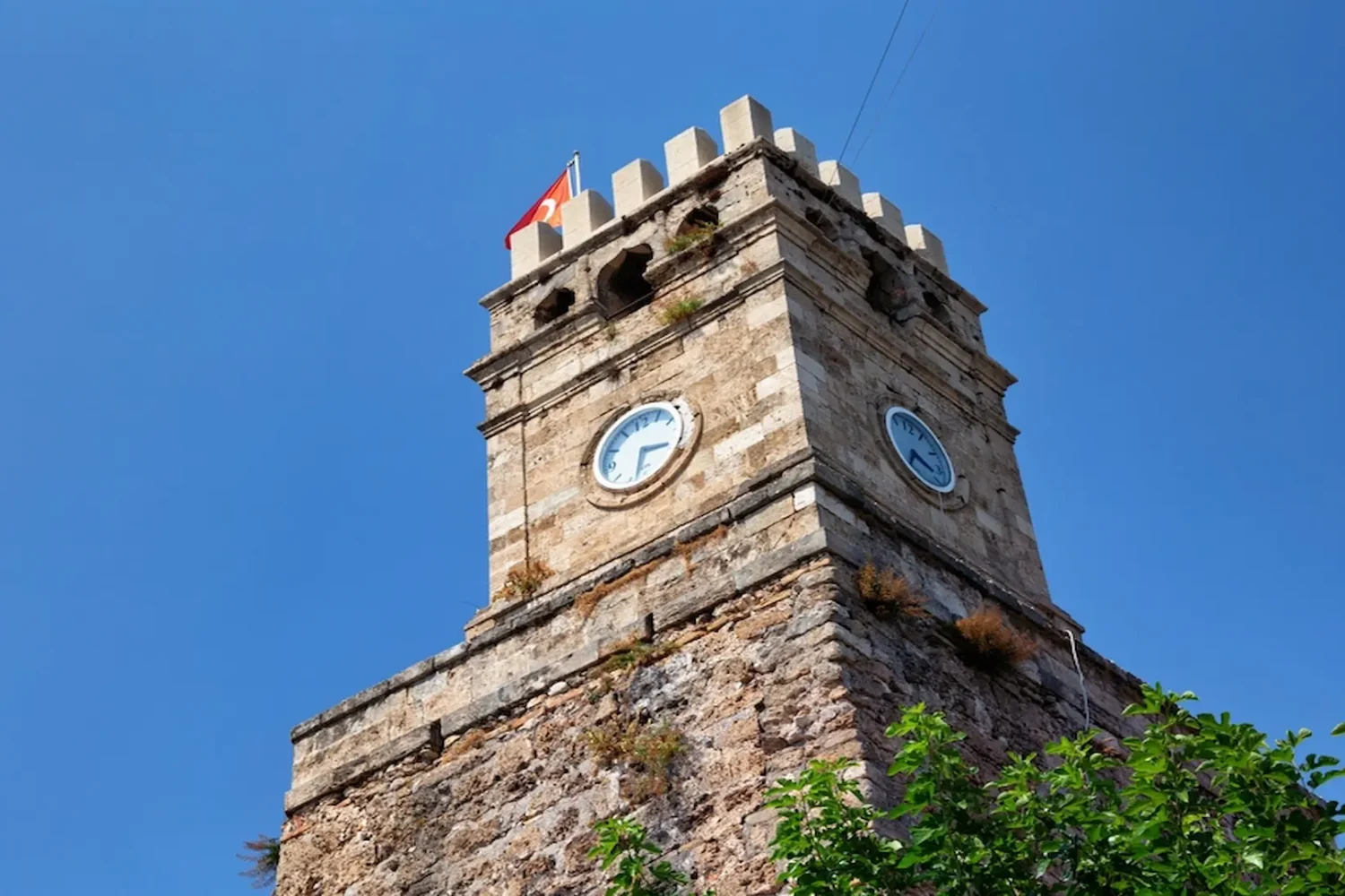 Stone clock tower with Turkish flag in Antalya Old Town