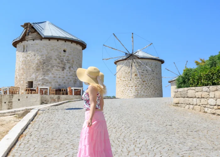 Tourist visiting traditional stone windmills in Cesme