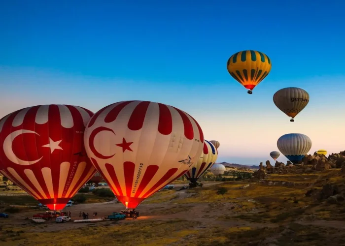 Cappadocia hot air balloons decorated with Turkish flags at sunrise