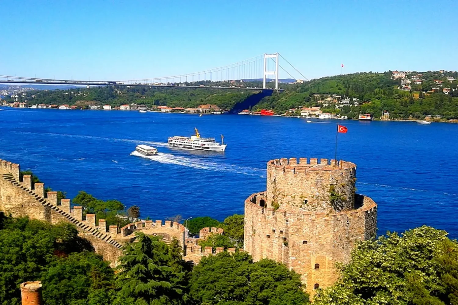 Rumeli Fortress tower and Bosphorus Bridge with boats on the water