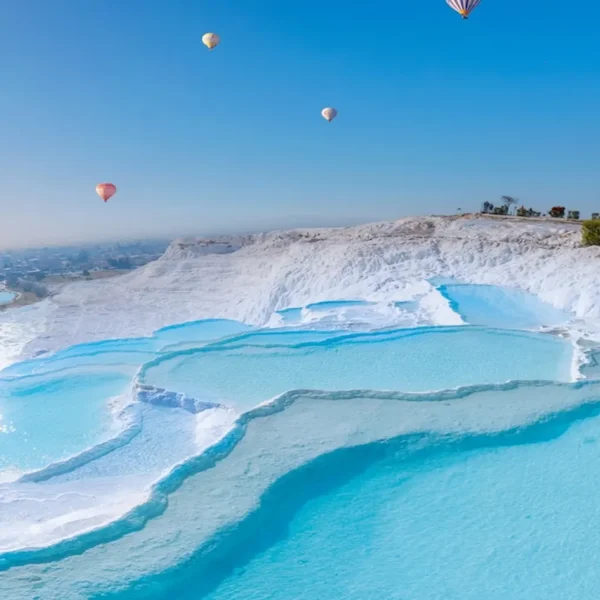 Colorful hot air balloons flying over Pamukkale travertine terraces