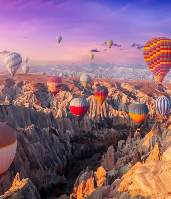 Colorful hot air balloons flying over Cappadocia’s valleys and fairy chimneys at sunrise