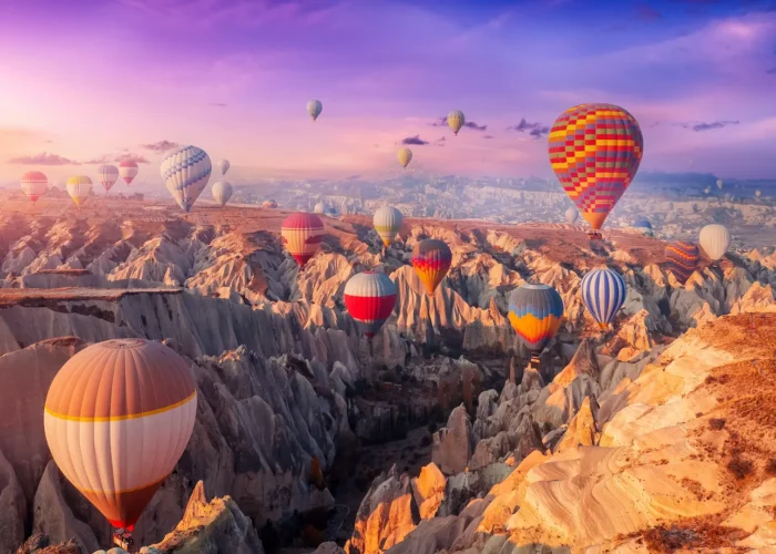 Colorful hot air balloons flying over Cappadocia’s valleys and fairy chimneys at sunrise