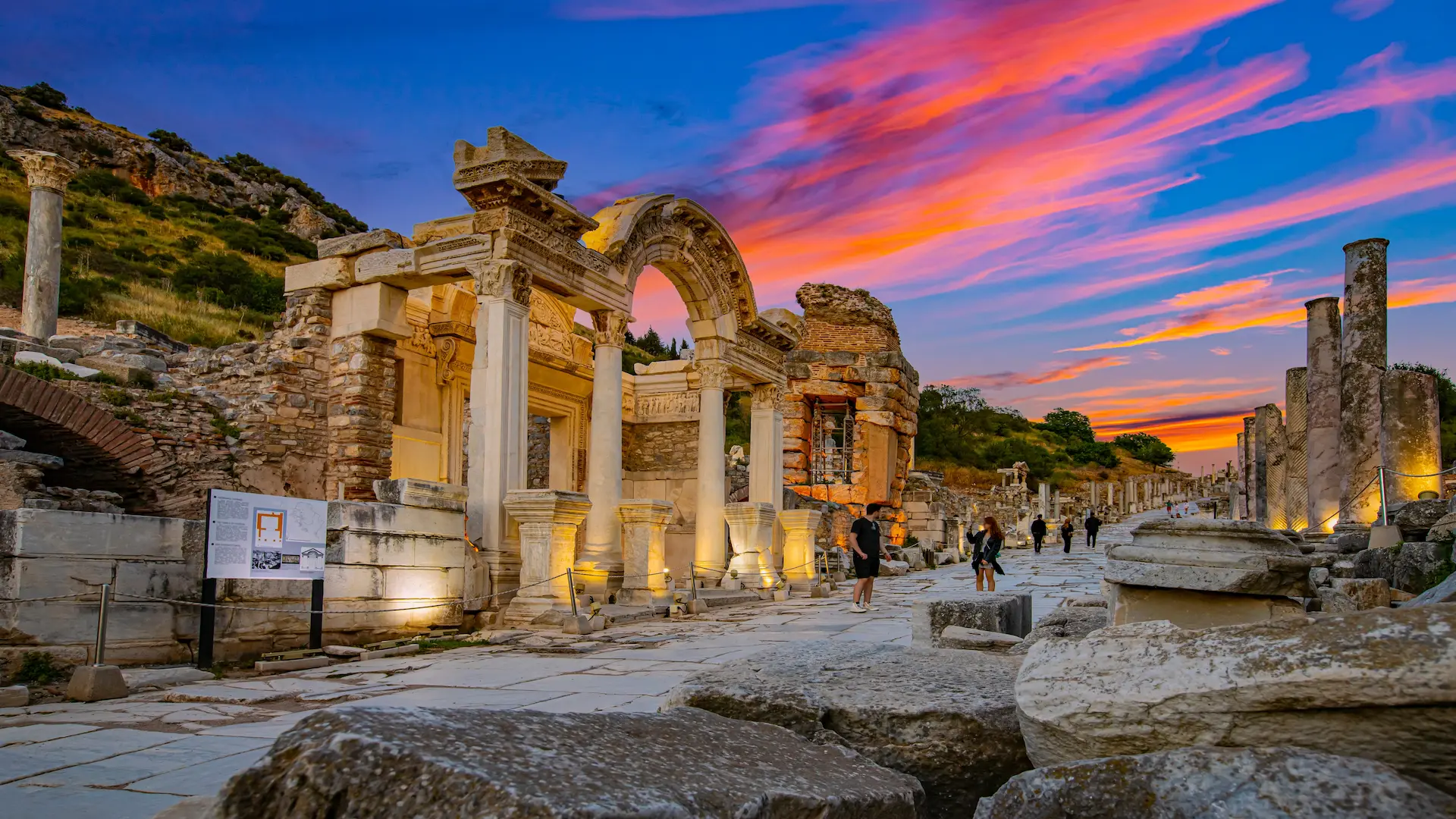 Sunset view of Hadrian’s Temple in Ephesus with tourists walking nearby