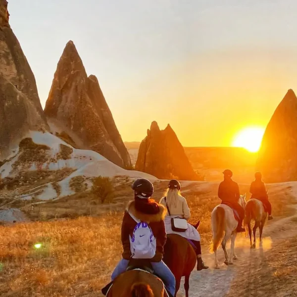 Travelers enjoying a horseback riding tour at sunset in Cappadocia, Turkey
