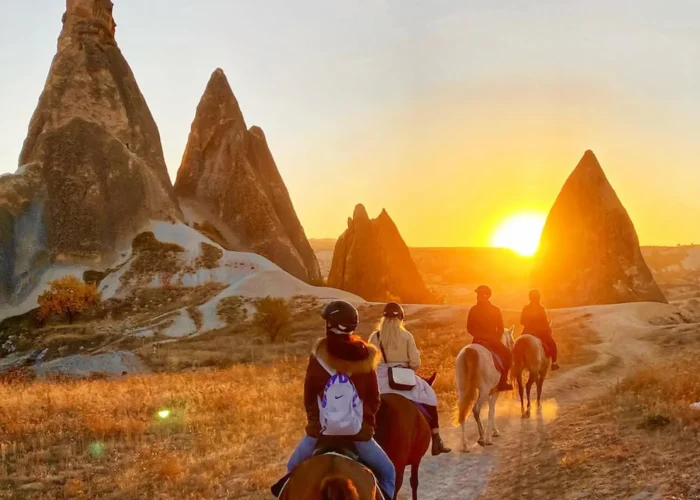 Travelers enjoying a horseback riding tour at sunset in Cappadocia, Turkey