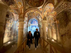 Visitors walking inside a frescoed cave church in Goreme Cappadocia